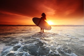 Surfer woman on beach at sunset. Beautiful surfer woman on the beach at sunset