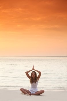 Yoga at sunset. Woman in lotus yoga pose at sunset on the beach