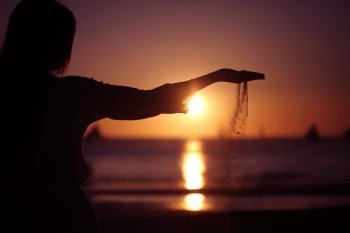 Woman pouring sand. Woman pouring sand on tropical sea beach at sunset