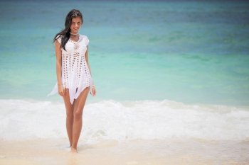 Woman in dress on beach. Beautiful young woman in dress on beach with hands raised