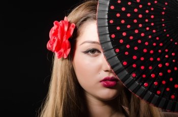 Beautiful young woman with flower and fan