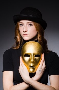 Redhead woman in hat  iwith mask in hypocrisy consept against dark  grey background