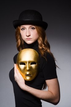Redhead woman in hat  iwith mask in hypocrisy consept against grey background