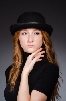 Redhead girl in hat against grey background