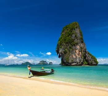 Thailand tropical vacation concept background - Long tail boat on tropical beach with limestone rock, Krabi, Thailand