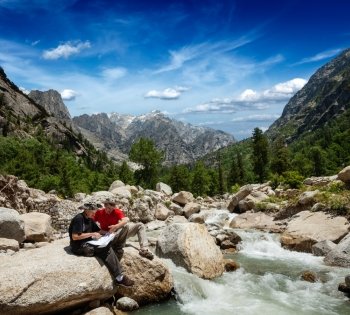 Hiker trekkers read a trekking map on trek in Himalayas mountains. Himachal Pradesh,India