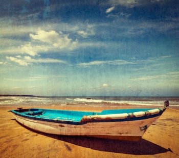 Vintage retro hipster style travel image of boat on a beach, India  with grunge texture overlaid