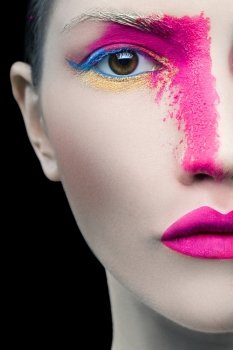 Close up portrait of a girl with pink artistic make up on black background