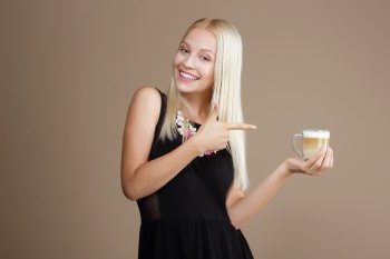 Happy Blond Woman Points Out to the Cup of Coffee