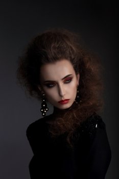 Fashionable woman with high hair, a photo session in the studio. Red lips, professional makeup.