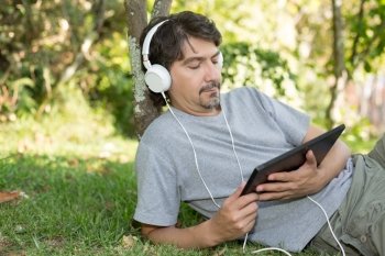 Young man relaxing with a tablet computer at a garden