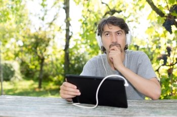 Young man relaxing with a tablet computer at a garden