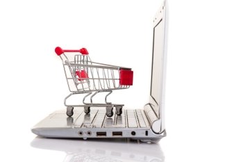 Studio shot of a  shopping cart over a laptop computer
