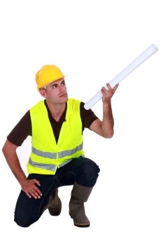 Tradesman holding up a rolled-up blueprint