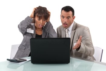 Two business people shocked by laptop