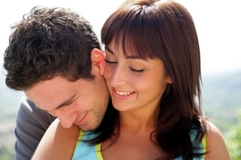 Head and shoulders of a young couple embracing in the sunshine