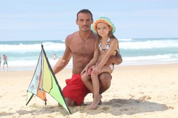 Man and little girl playing with kite at the beach