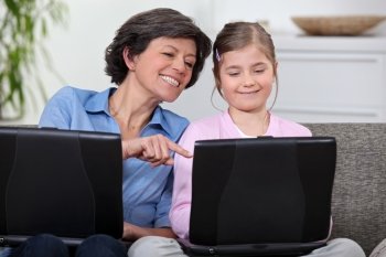 A mother and her daughter on their laptops.