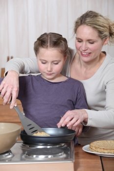 Woman and little girl cooking pancakes