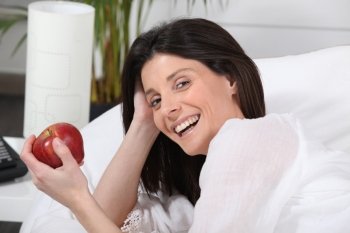 Woman in bed with apple in hand