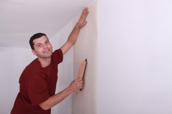 Decorator smoothing down wallpaper with a brush