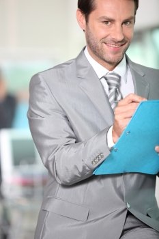 Businessman writing notes in a blue folder