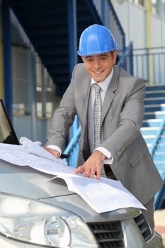 Architect looking at plans on a car bonnet