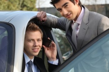 Two businessman by a car.