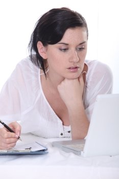 Young woman using a laptop computer and  a pen and paper