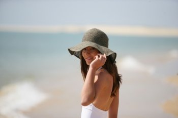An attractive woman wearing a floppy hat at the beach