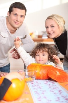 a little child  eating a pumpkin and his parents