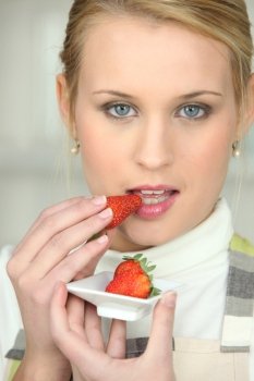 blonde woman tasting strawberry