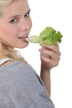 Blond woman eating lettuce leaf
