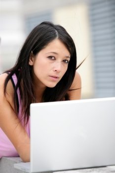 Pretty young woman laid in front of laptop