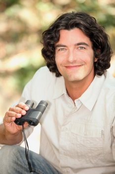 A smiling man with a pair of binoculars