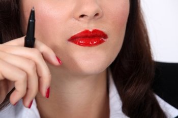 Businesswoman wearing red lipstick and holding pen