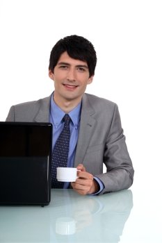 Businessman sat at desk drinking an espresso