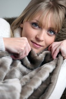 Blond woman relaxing under blanket