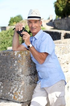 Senior man at a citadel with a pair of binoculars