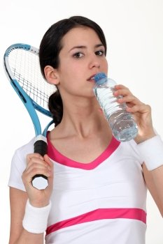 A tenniswoman taking a sip of water.