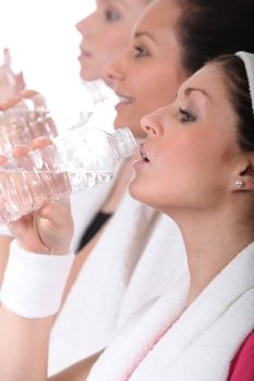 Women in gym drinking from water bottles