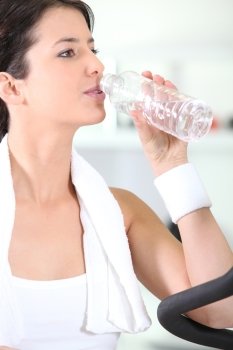 Woman drinking from water bottle in gym