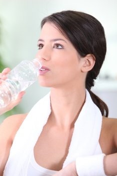 Woman drinking a bottle of water after a workout
