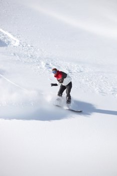 Adventurous man snowboarding down hill