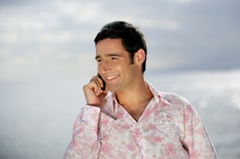 Smiling man on the phone by the coast