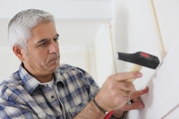 Grey-haired man repairing house