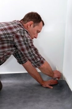 Man pushing lino flooring to fit into a corner