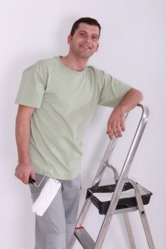 Man using a roller to paint a room white
