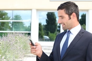 Handsome businessman texting on a mobile phone