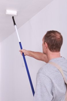 Decorator painting a ceiling white